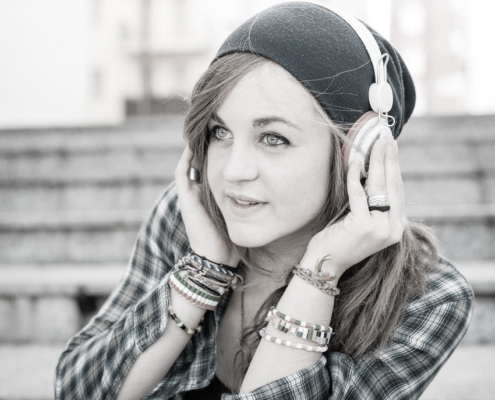 A woman wearing headphones and a plaid shirt outdoors.